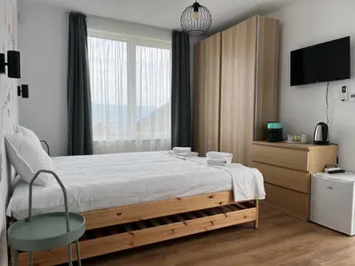 a bedroom with a bed with a chair and a tv at Villa YoSi - apartments in Sapareva Banya