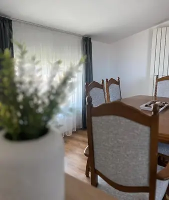a dining room table and chairs with a vase of flowers at Villa YoSi - apartments in Sapareva Banya