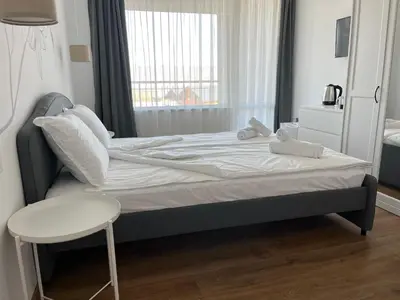 a bedroom with a large bed with a chair and a window at Villa YoSi - rooms in Sapareva Banya