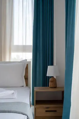 a bedroom with two beds and a window with blue curtains at Студио 9 Парк Панорама in Hisarya