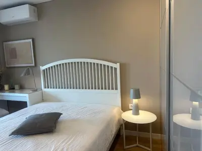a bedroom with a white bed and a table with a lamp at Апартамент В 54 в Сграда МОНА in Sofia