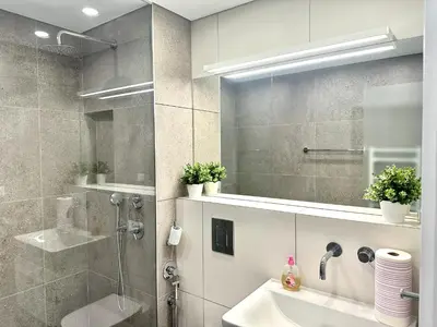 a bathroom with a shower and a sink and a mirror at Апартамент В 54 в Сграда МОНА in Sofia