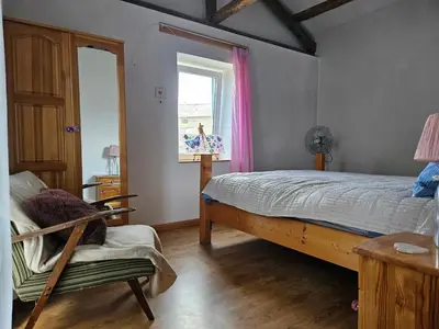 a bedroom with a bed and a chair and a window at Balkan Barn in Tŭzha