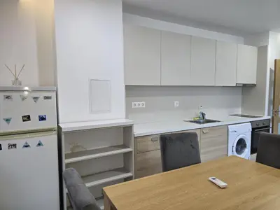 a kitchen with white cabinets and a table and a refrigerator at The Ascent in Sofia