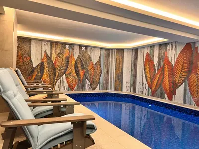a swimming pool in a hotel room with chairs next to it at Ardo Hill Spa Hotel and Restaurant in Sarnitsa