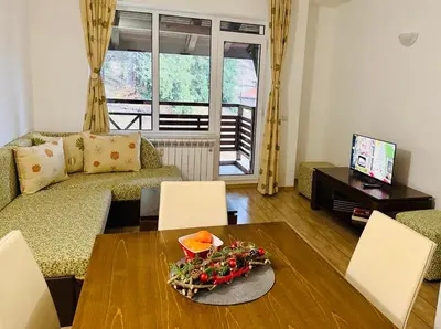 a living room with a table and a couch at Forest Retreat, Stream Resort, Pamporovo in Stoykite