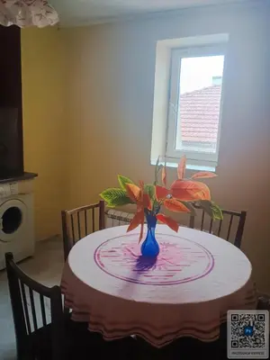 a table with a blue vase with flowers on it at Uspeh bg in Plovdiv