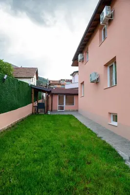 a backyard of a pink building with a green yard at Къща Инфинити Лукс и Уют, Вплетени в Спомени in Sapareva Banya