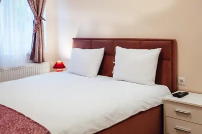 a bedroom with a bed with white sheets and a window at Къща Инфинити Лукс и Уют, Вплетени в Спомени in Sapareva Banya