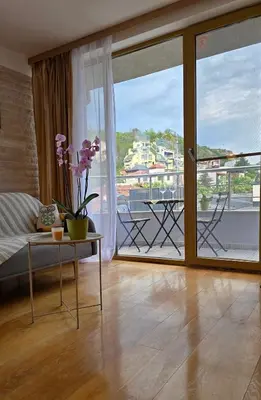 a living room with a table and a large window at Арт мезонет под тепето in Plovdiv