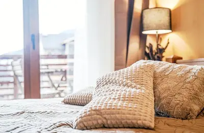 a bedroom with a bed with pillows and a window at Forest nest Cozy apartment white balcony on the hill in Bansko