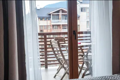 a room with a balcony with a table and chairs at Forest nest Cozy apartment white balcony on the hill in Bansko