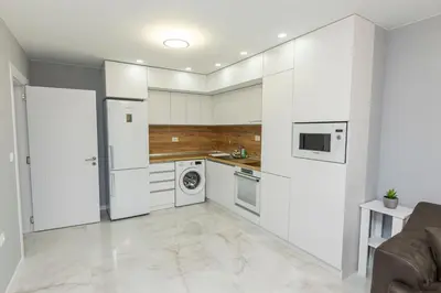 a kitchen with white cabinets and a washer and dryer at White lux in Sandanski