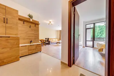 a kitchen with wooden cabinets and a dining room at Forest Harmony 1BD with Balcony & Parking by Flat Manаger in Smolyan