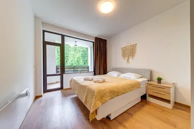 a bedroom with a large bed and a window at Forest Harmony 1BD with Balcony & Parking by Flat Manаger in Smolyan