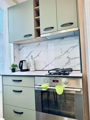 a kitchen with a stove and white cabinets at Unique flat with balcony in the heart of the city in Kyustendil