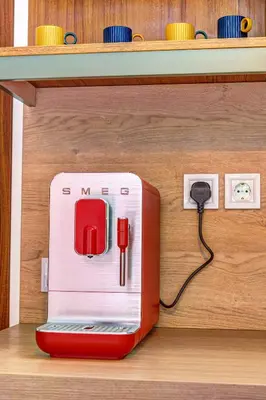 a red toaster plugged into an outlet on a shelf at Into the Woods - Charming Studio by Flat Manager in Smolyan