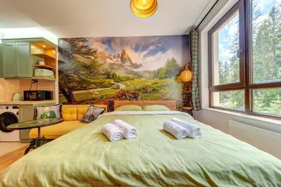 a bedroom with a large bed with a painting on the wall at Into the Woods - Charming Studio by Flat Manager in Smolyan
