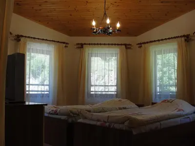 two beds in a bedroom with windows and a chandelier at Villa Persenk in Lyaskovo
