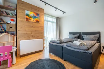 a bedroom with a large bed and a pink chair at Arte Apartment in Sofia