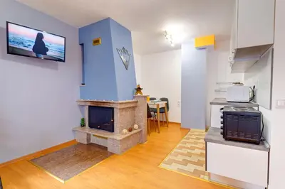 a living room with a fireplace and a kitchen at Colorful Retreat - 1BD next to the slopes by Flat Manager in Pamporovo