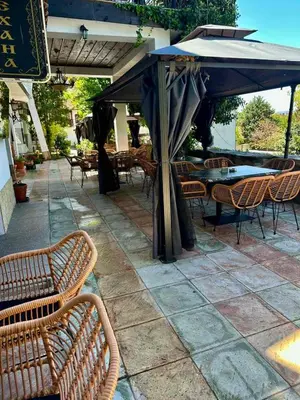 a patio with tables and chairs and an umbrella at Комлекс Кристо in Blagoevgrad