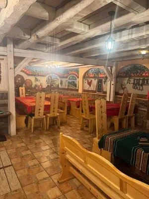 a restaurant with wooden tables and chairs and paintings on the walls at Комлекс Кристо in Blagoevgrad