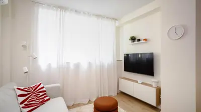 a white living room with a tv and a window at Cozy 1BD Apartment next to NDK by Flat Mаnager in Sofia