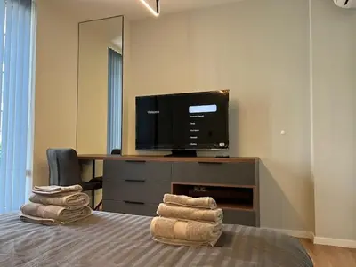 a bedroom with a bed and a tv and towels at Gran Capital - Vodoley Rose Garden !Free Parking! in Sofia