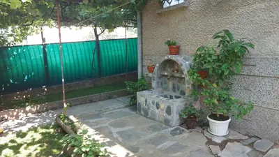 a garden with a stone fireplace next to a building at Бащината Къща in Sapareva Banya