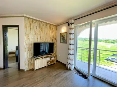 a living room with a tv and a sliding glass door at Апартамент Елегант - спа комплекс Аква Терми in Krasnovo