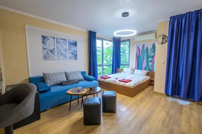 a living room with a blue couch and a bed at Comfy & Chic Apartment , SWU , FREE Parking in Blagoevgrad
