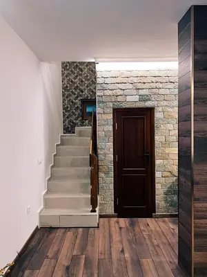 a hallway with stairs and a door and a stone wall at Alpine View Villa in Razlog