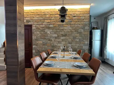 a dining room with a table with chairs and a brick wall at Alpine View Villa in Razlog