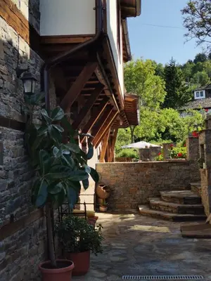 a house with a brick wall and a potted plant at Къщата на музиканта in Leshten