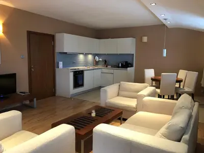 a living room with white furniture and a kitchen at Panorama Apartment in Pamporovo