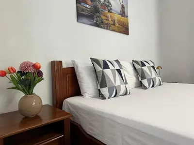 a bed with pillows and a vase with flowers on a table at TRIIBRIA Guest house in Trigrad