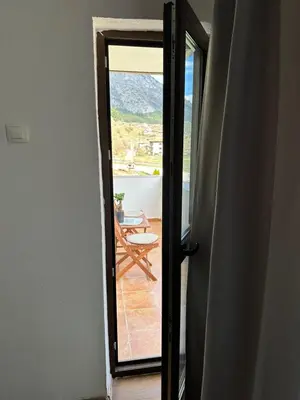 an open door to a balcony with a table on a deck at TRIIBRIA Guest house in Trigrad