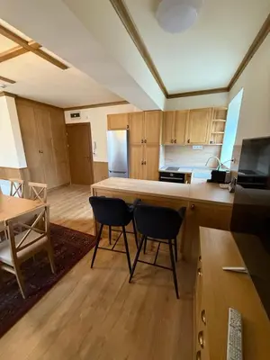 a kitchen with wooden cabinets and a table and chairs at Apartment 78 by the pool in Bansko