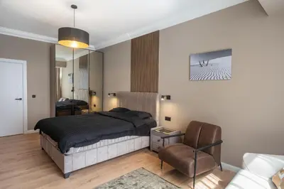a bedroom with a large bed and a chair at Amber Corner I Brand New Flat Top Location in Sofia