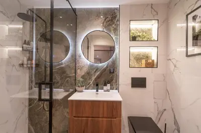 a bathroom with a sink and a shower with a mirror at Amber Corner I Brand New Flat Top Location in Sofia