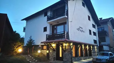 a white building with a balcony on the side of it at Guest House Raffe in Dobrinishte