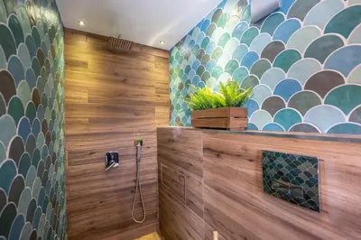 a bathroom with a shower with a tile wall at Leafy Loft in Sofia