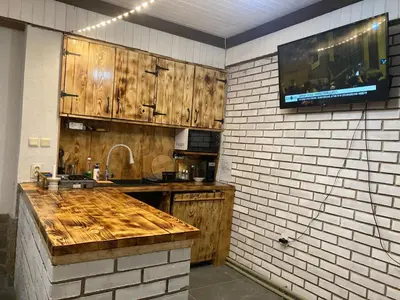 a kitchen with wooden cabinets and a tv on a wall at Къща за гости Рупчос 1 in Smolyan