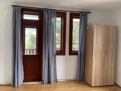 a room with two windows and a wooden door at Къща за гости Рупчос 1 in Smolyan