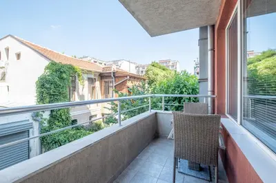 a balcony with two chairs and a view of buildings at Spacious 1 bedroom apartment in a lively center in Sofia