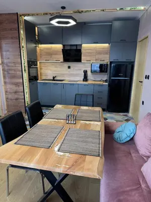 a dining room with a table and a kitchen at VeliApartmets in Velingrad