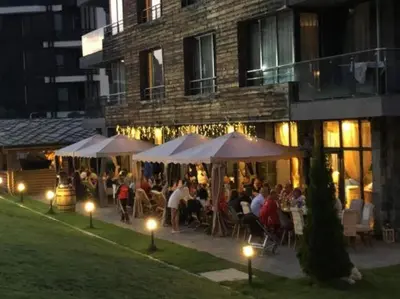 a group of people sitting under umbrellas outside a building at Ski Retreat Spa Pool and Mountain Views in Bansko