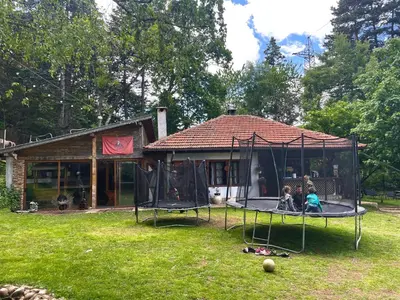 a house with a playground with two children on a trampoline at Kъщичка в полите на планина Витоша с коне и животни in Sofia