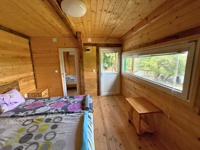 a bedroom with a bed and a table in a cabin at Kъщичка в полите на планина Витоша с коне и животни in Sofia